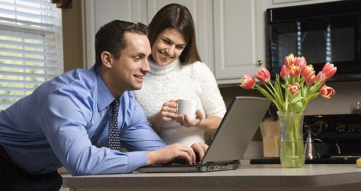 man and woman looking at laptop in kitchen