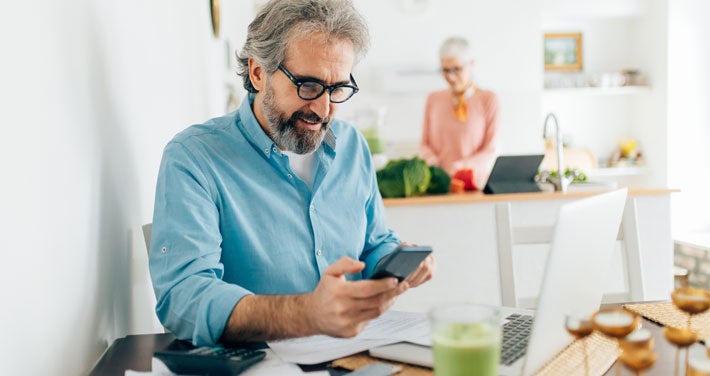 senior man using calculator at kitchen table