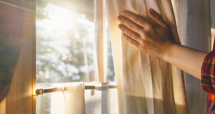 hand opening curtain to let sunlight in