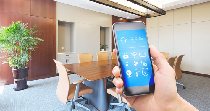 hand in office holding phone with smart office app on screen