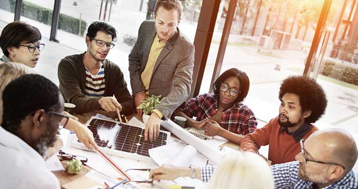 A business team around a table looking at a solar panel