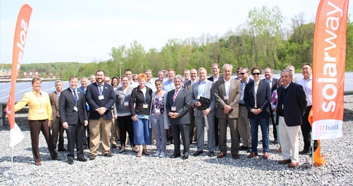 attendees at Solarway ribbon cutting ceremony pose in front of solar array