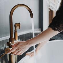 hands checking bath faucet temperature