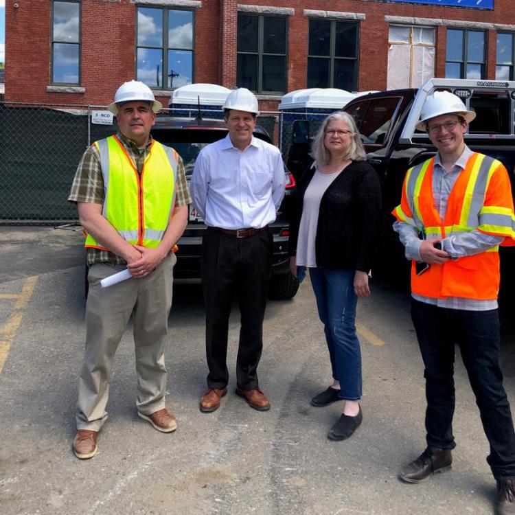 workers pose on street in front of Moran Square building construction