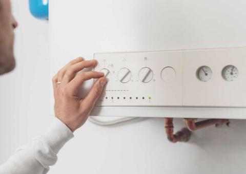 Man adjusting wall thermostat