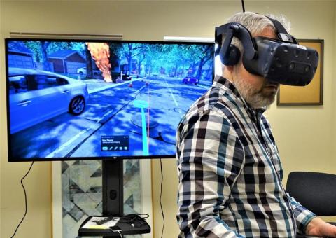 Unitil employee with virtual reality goggles stands in front of simulator